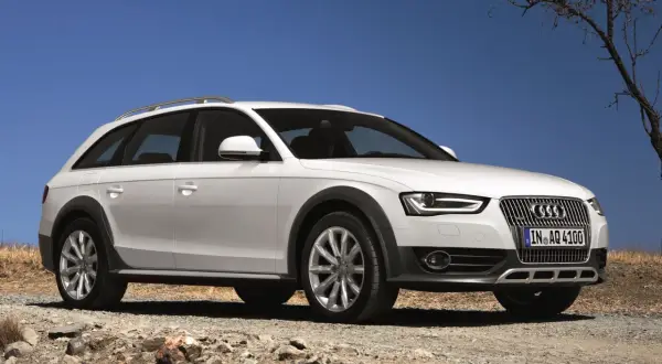 Białe Audi A4 B8 Allroad quattro na kamienistej drodze pod błękitnym niebem.