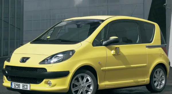 Żółty Peugeot 1007 z przesuwnymi drzwiami na tle nowoczesnego budynku.