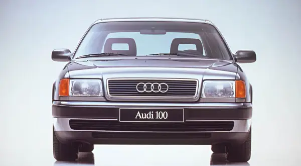 Klasyczne Audi 100 z lat 90. prezentuje się elegancko na jasnym tle.