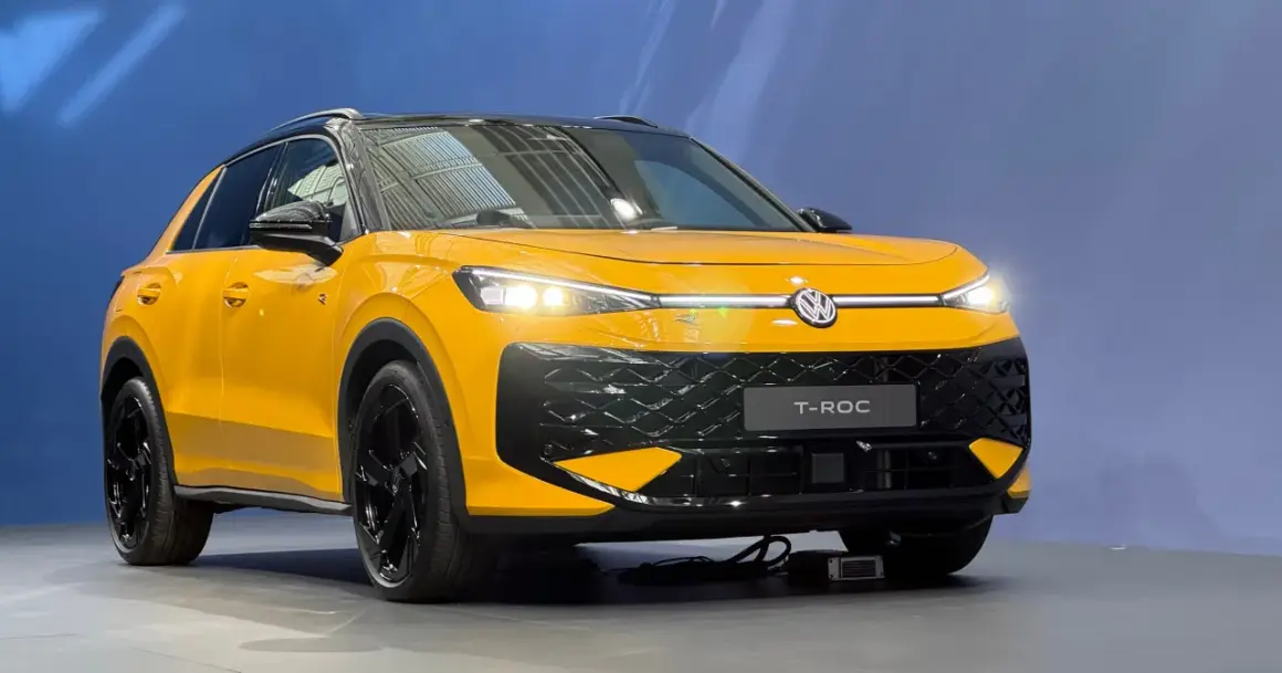 Żółty Volkswagen T-Roc z czarnym dachem i felgami. Zbliżenie na przód auta, gdzie widoczne są światła LED i atrapa chłodnicy. T roc wymiary sugerują kompaktowy SUV.