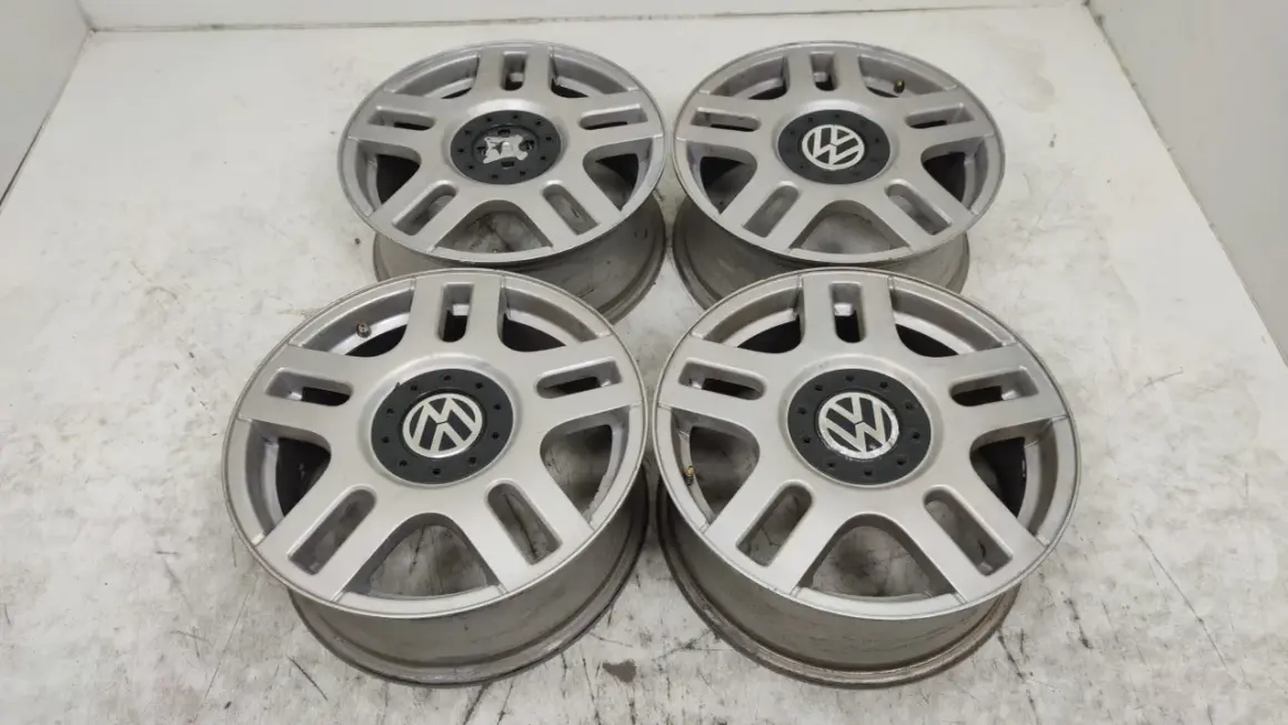 Cztery srebrne felgi aluminiowe Volkswagen z czarnym środkiem i logo VW.