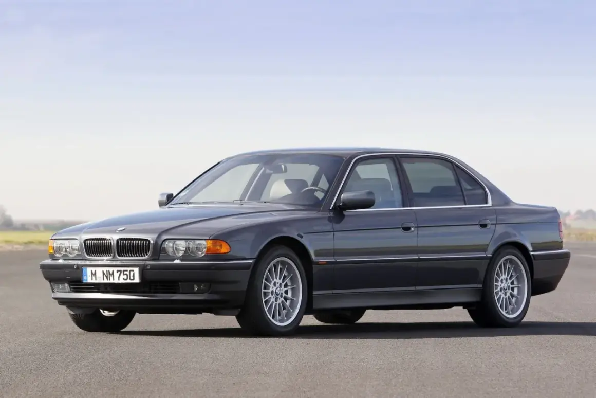 Ciemnoszary sedan BMW serii 7 (E38) z silnikiem V12 na tle nieba.
