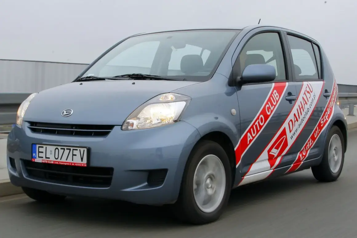 Niebieski Daihatsu Sirion z napisem "AUTO CLUB DAIHATSU" na boku, jadący po drodze.
