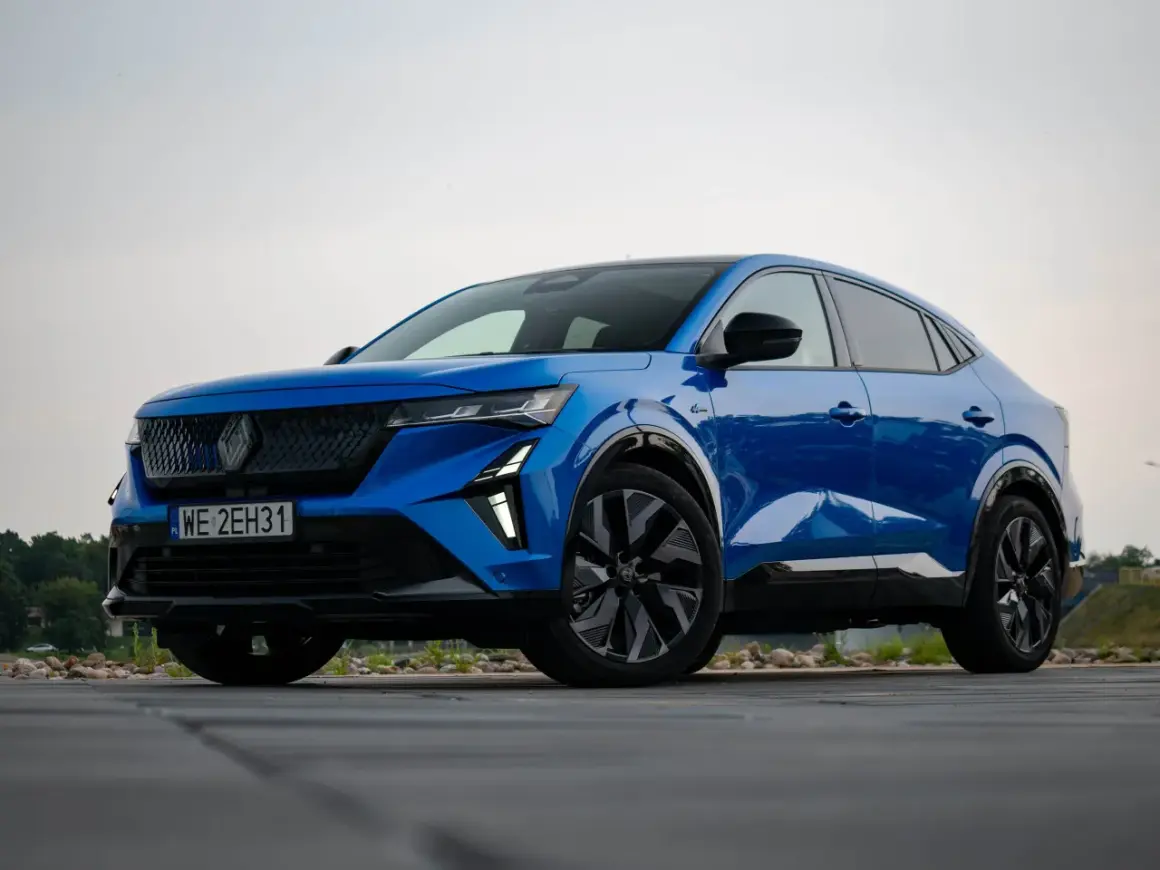 Niebieski Renault Rafale, SUV coupe, zaparkowany na drewnianym tarasie.
