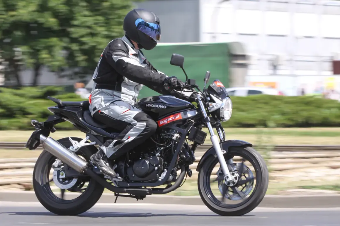 Motocyklista w pełnym stroju pędzi na czarnym Hyosung GT 125, ciesząc się jazdą.