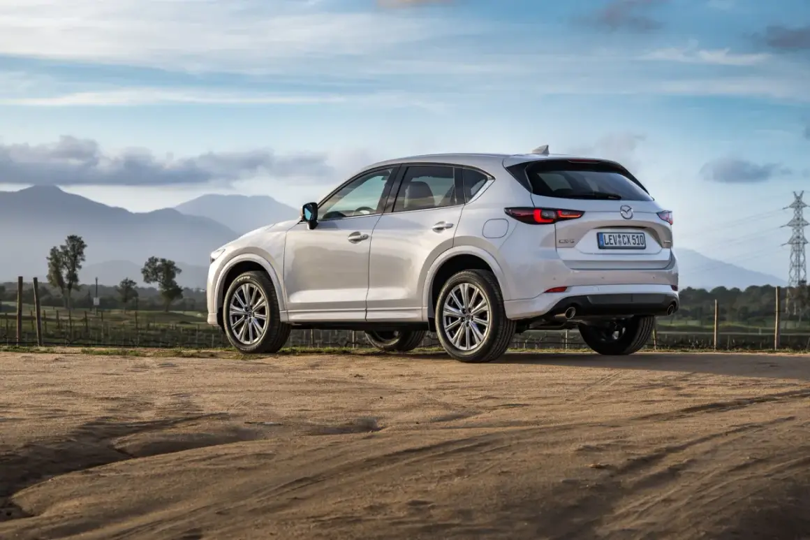 Biała Mazda CX-5 na tle gór i nieba. Elegancki SUV gotowy na przygodę.