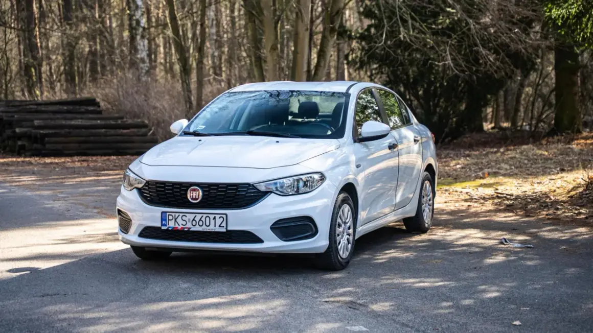 Biały Fiat Tipo sedan zaparkowany na leśnej drodze.