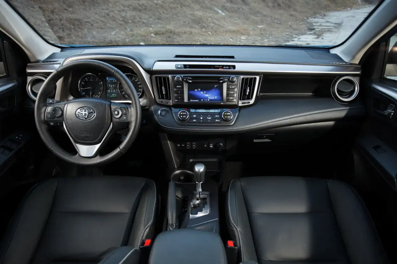 Wnętrze Toyoty RAV4 2005 z czarną skórzaną tapicerką, kierownicą i panelem multimedialnym.