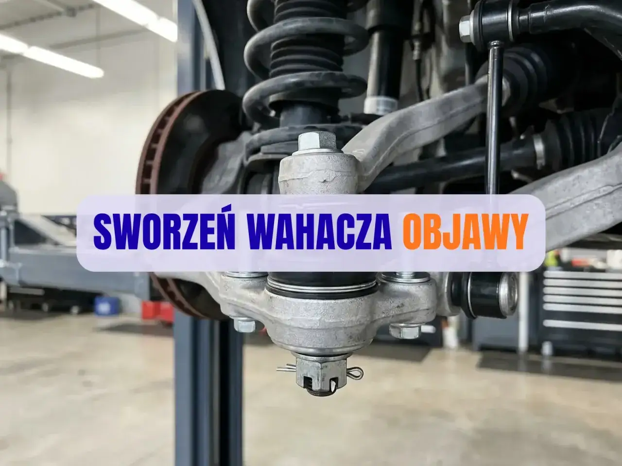 Widok na element zawieszenia samochodu. Tekst na obrazku: