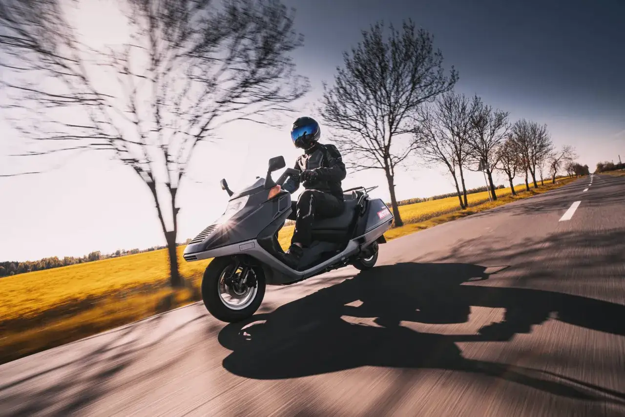 Japoński motocykl mknie po drodze wśród drzew i kwitnącego pola.