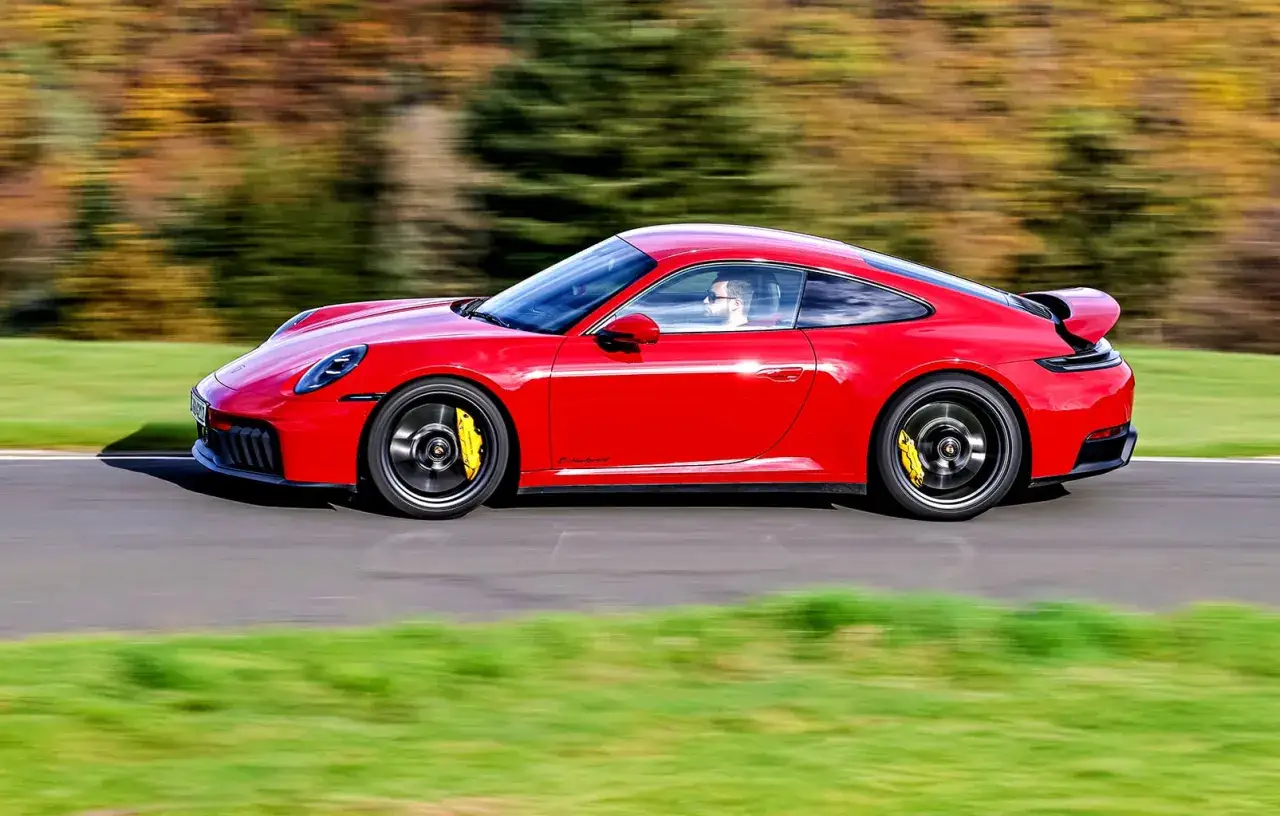 Czerwone Porsche 911 Carrera 4 GTS pędzi po torze, żółte zaciski hamulcowe kontrastują z felgami.