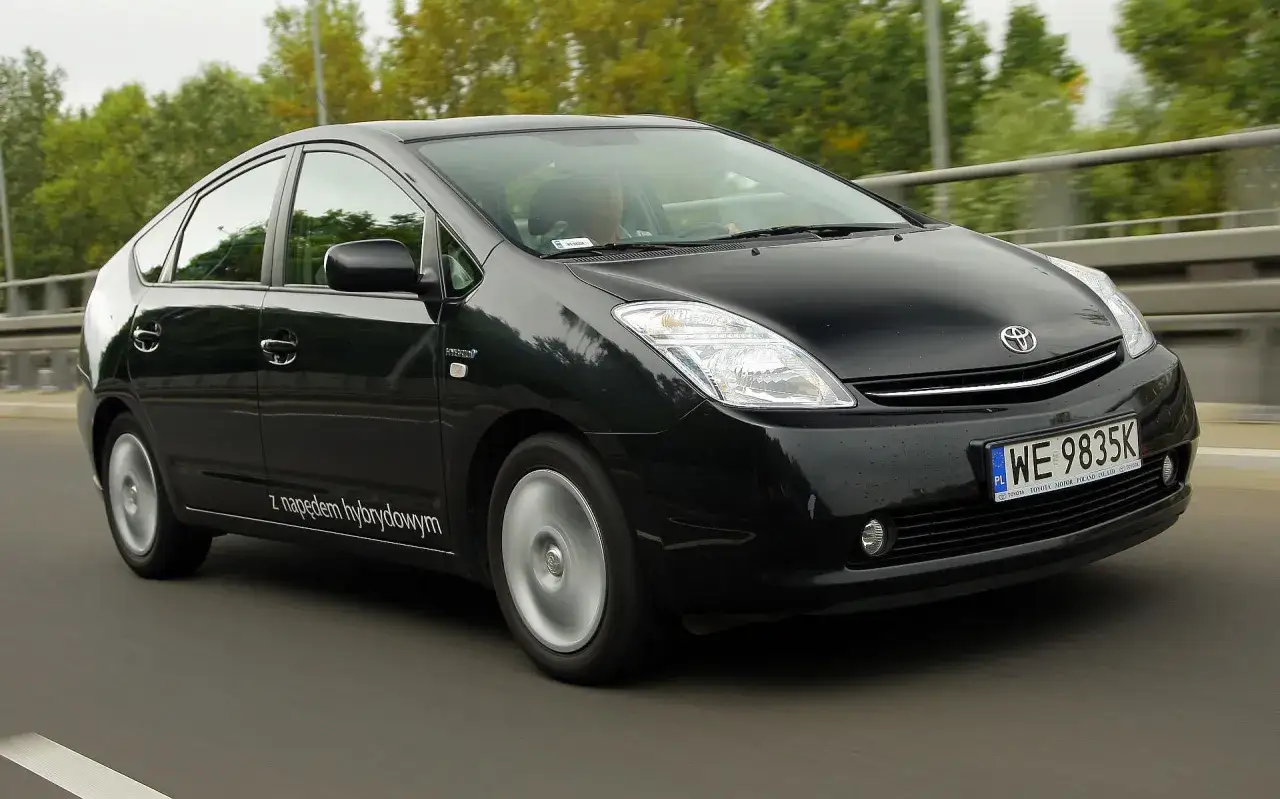 Czarny Toyota Prius 2 z napędem hybrydowym jedzie po drodze.