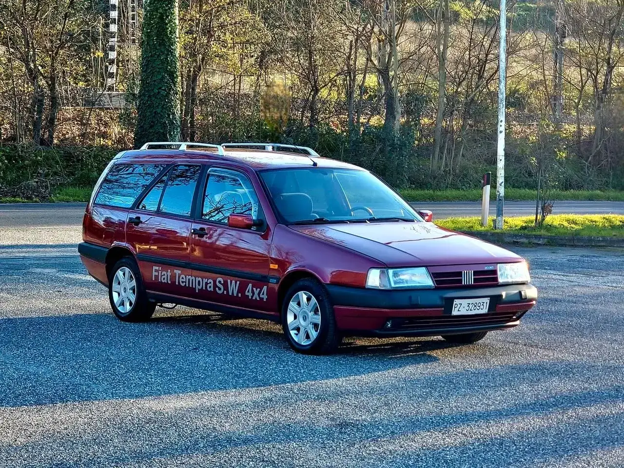 Ciemnoczerwony Fiat Tempra S.W. 4x4 na tle drzew.