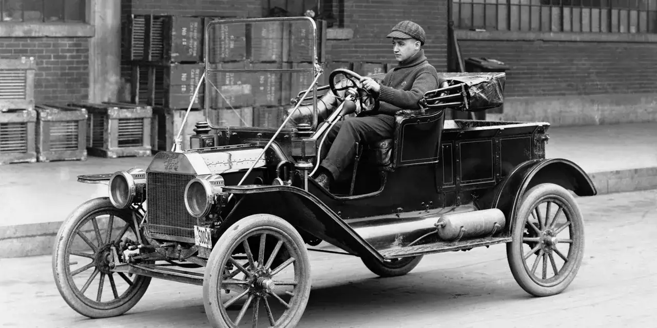 Mężczyzna w czapce prowadzi zabytkowego Forda Model T.