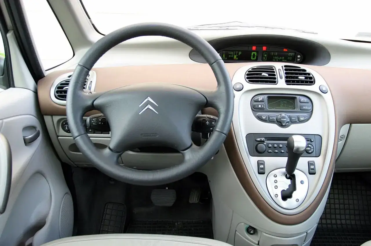 Wnętrze Citroëna Xsara Picasso: kierownica, deska rozdzielcza z radiem i panelem klimatyzacji, dźwignia zmiany biegów.