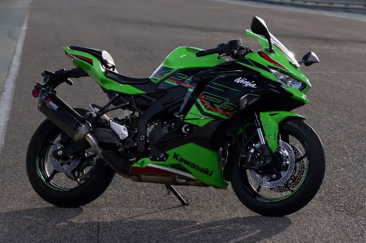 Zielono-czarny motocykl Kawasaki Ninja ZX4RR z wydechem Akrapovič na torze wyścigowym.
