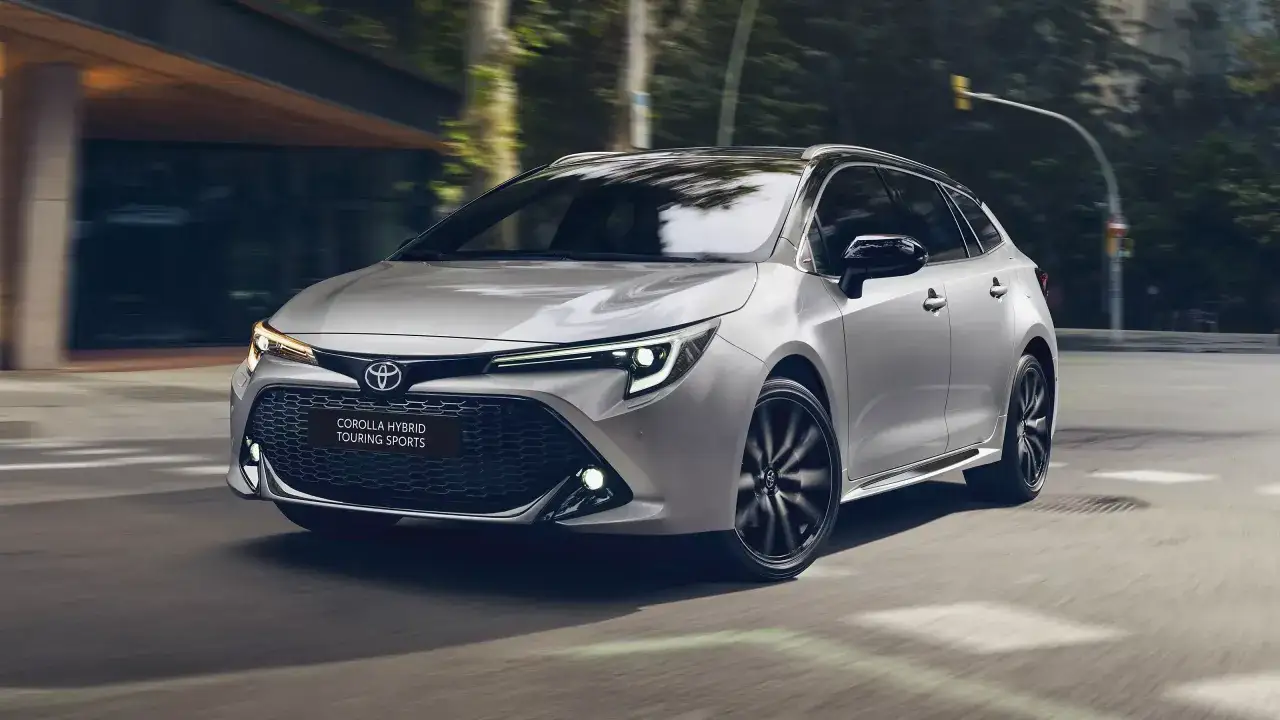 Srebrna Toyota Corolla 1.8 Hybrid Touring Sports pędzi ulicą, zamazane tło sugeruje ruch.
