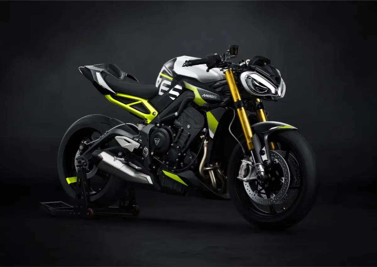 Nowoczesny motocykl Triumph Street Triple w białym i czarnym malowaniu z neonowo-żółtymi akcentami, z przodu złote amortyzatory.