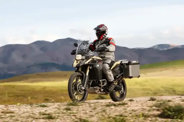 Motocyklista w pełnym rynsztunku przemierza górskie tereny na motocyklu BMW 800 GS.