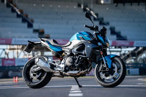 Niebiesko-szary motocykl BMW F900R na torze wyścigowym, gotowy do jazdy.