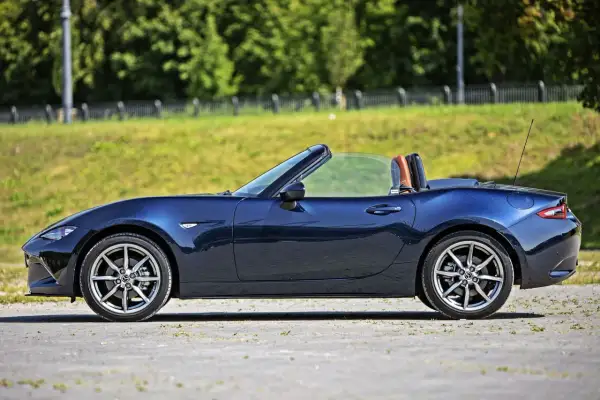 Granatowy roadster z otwartym dachem, widok z boku.