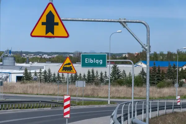 Znaki drogowe: pierwszeństwo przejazdu, przejazd kolejowy, nazwa miejscowości Elbląg.