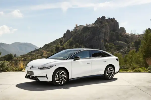 Biały Volkswagen ID.7 na tle malowniczego, skalistego krajobrazu z wioską na wzgórzu.