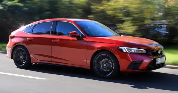 Czerwony Honda Civic 11 na drodze, z rozmytym tłem drzew.