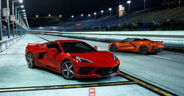 Dwa Chevrolet Corvette C8, czerwony i pomarańczowy, na nocnym torze wyścigowym. Sprawdź aktualną corvette c8 cena!