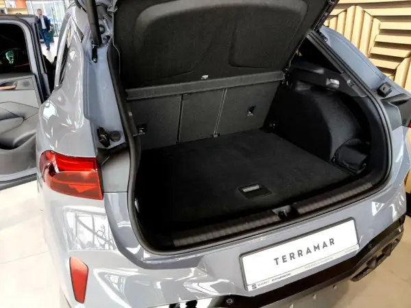 Otwarty bagażnik szarego SUV-a Cupra Terramar z widocznym wnętrzem i tablicą rejestracyjną.