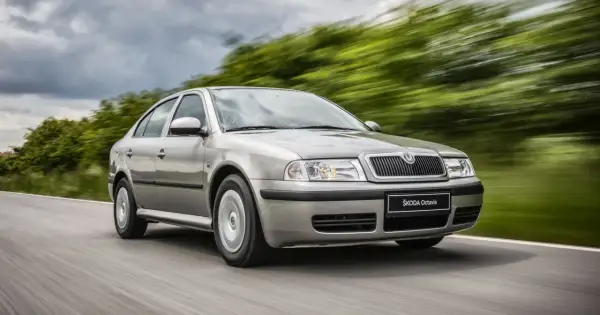 Srebrna Škoda Octavia jedzie po drodze, otoczona rozmytą zielenią. Sprawdź atrakcyjną Škoda Octavia cenę!