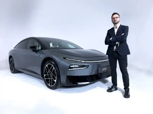 Elegancki mężczyzna w garniturze stoi obok szarego XPeng P7.