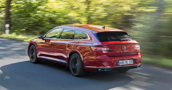 Czerwony Volkswagen Arteon Shooting Brake w ruchu na tle rozmytego krajobrazu.