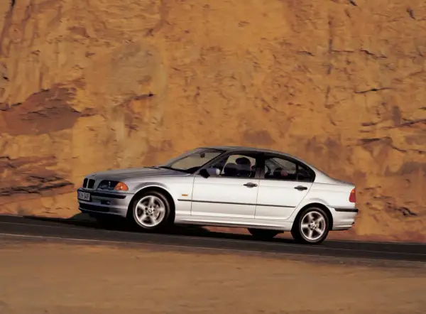 Srebrne bmw e46 330i sunie po drodze na tle skalistego, pomarańczowego zbocza.