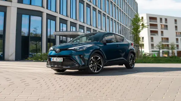 Elegancka, ciemnozielona Toyota hybryda na tle nowoczesnych budynków. Sprawdź atrakcyjną toyota hybryda cena!