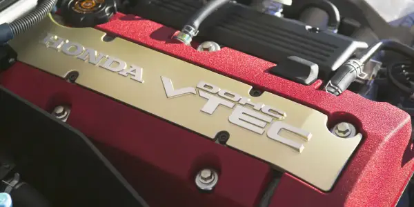 Złota pokrywa silnika Honda z napisem VTEC i czerwonymi akcentami.